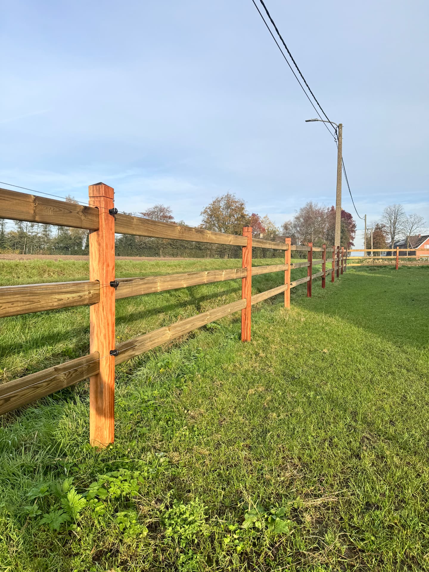 Briljant-omheining met drie liggers langs een groen veld