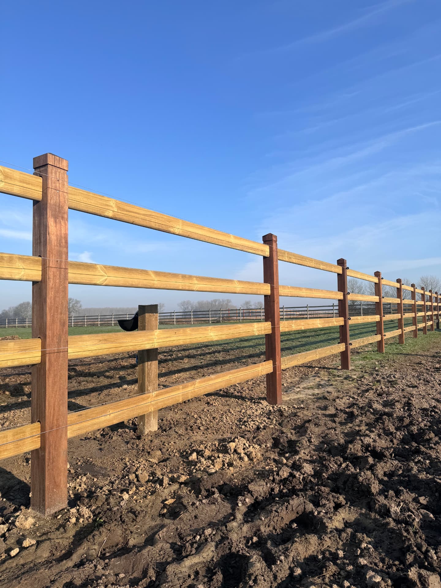 Briljant-omheining met vier liggers en draadwerk, met bouwland op de voorgrond