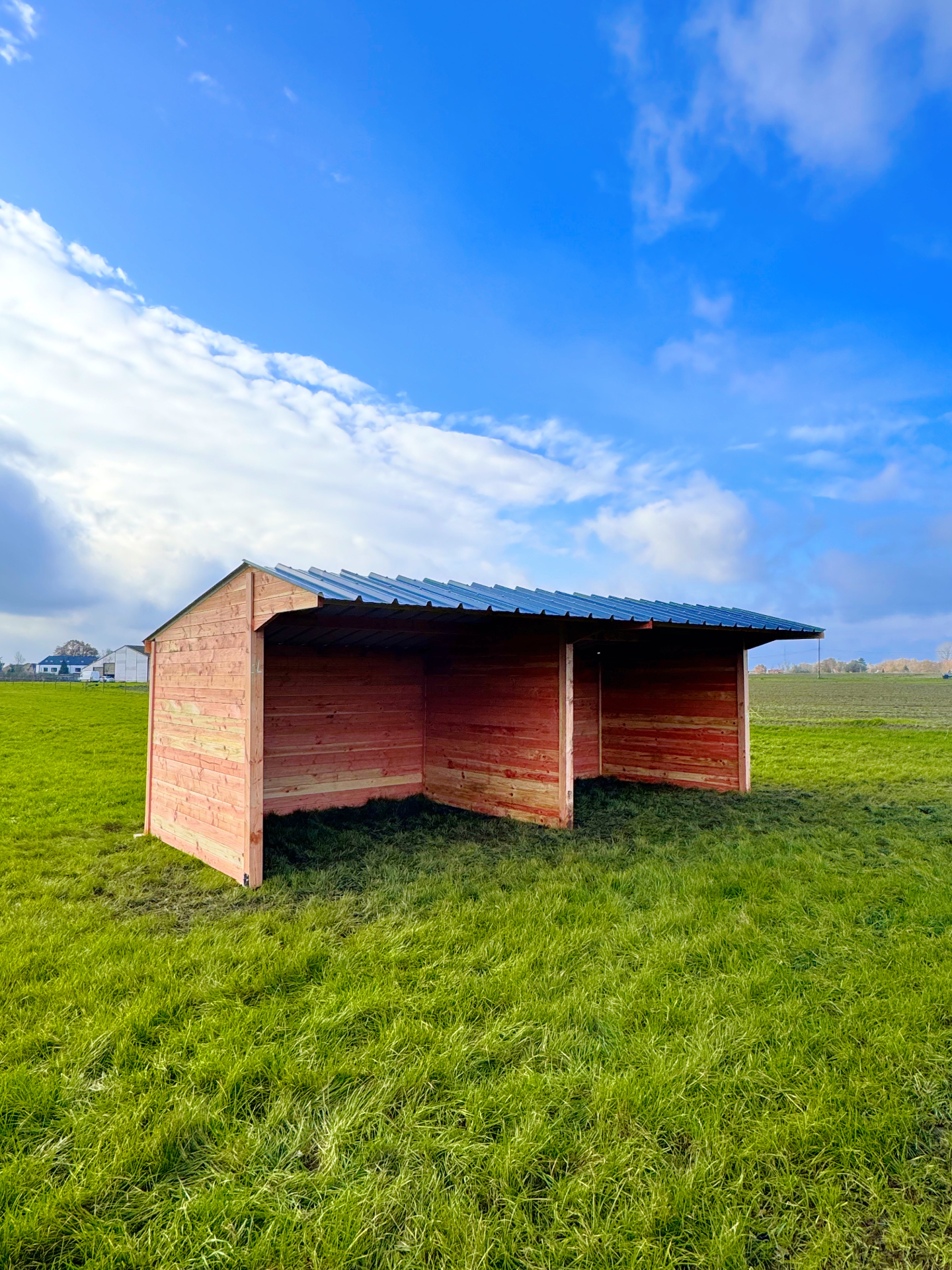 Houten schuilstal op een grasweide